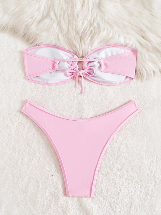 Pink bikini set with white bow on a fluffy white surface