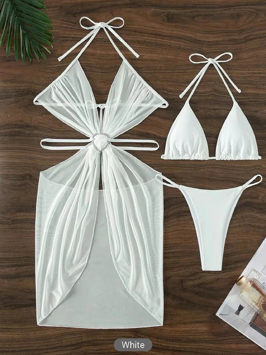 White bikini set with a sheer overlay on a wooden surface