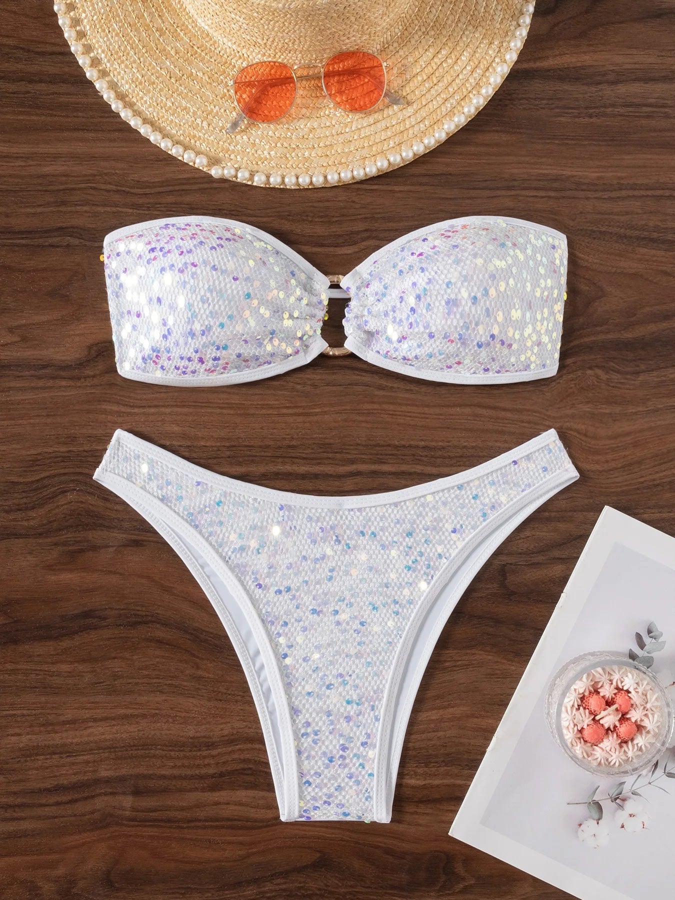 Sequined bikini set on a wooden surface with a hat and sunglasses.